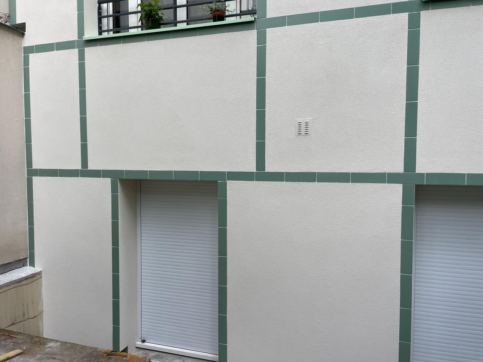 Finition de l'enduit blanc et des bandeaux verts autour d'une fenêtre
