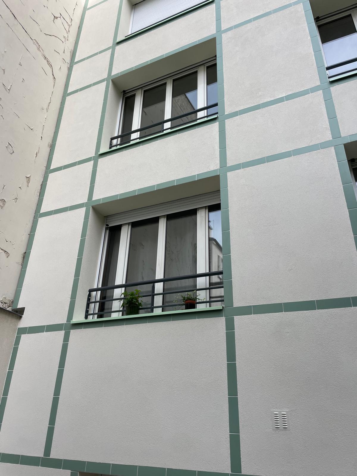 Détail des fenêtres et des bandeaux verts de la façade rénovée
