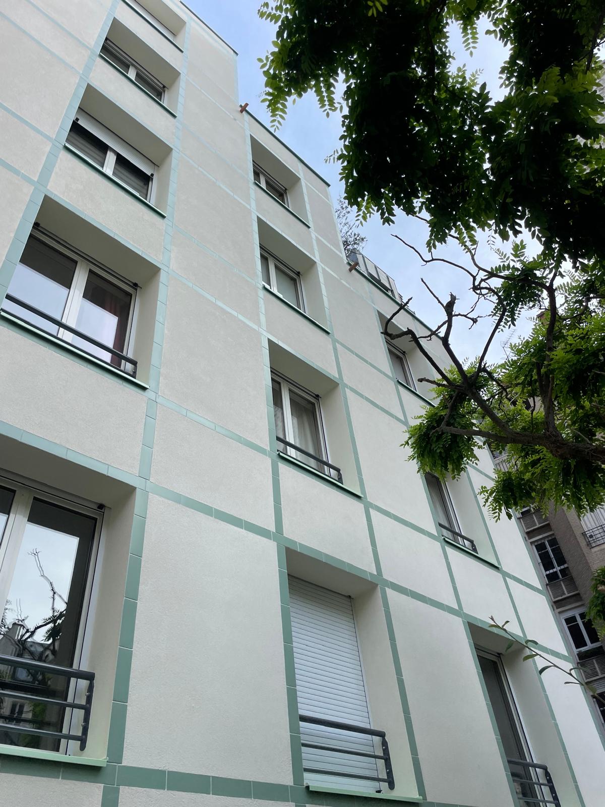 Vue en contre-plongée de la façade blanche rénovée et de ses fenêtres