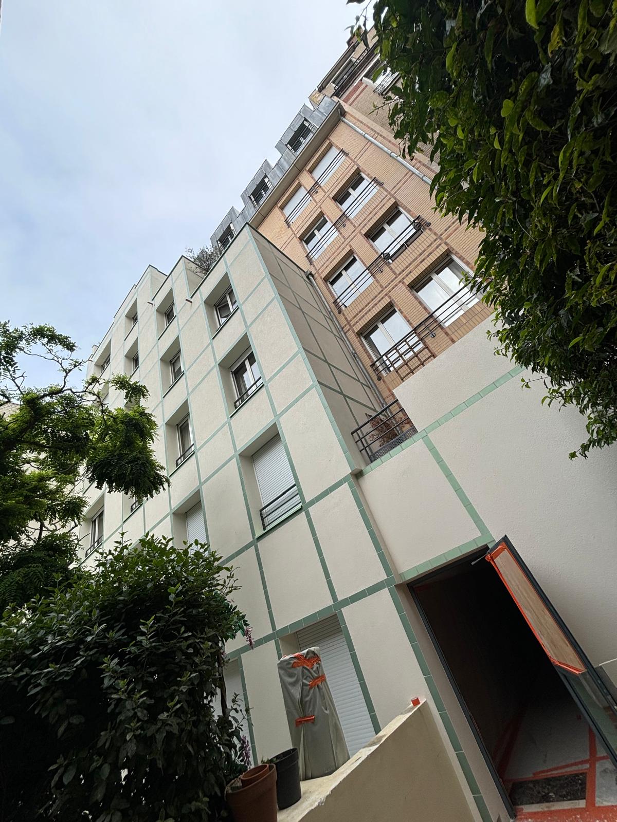 Façade blanche rénovée vue depuis le pied de l'immeuble